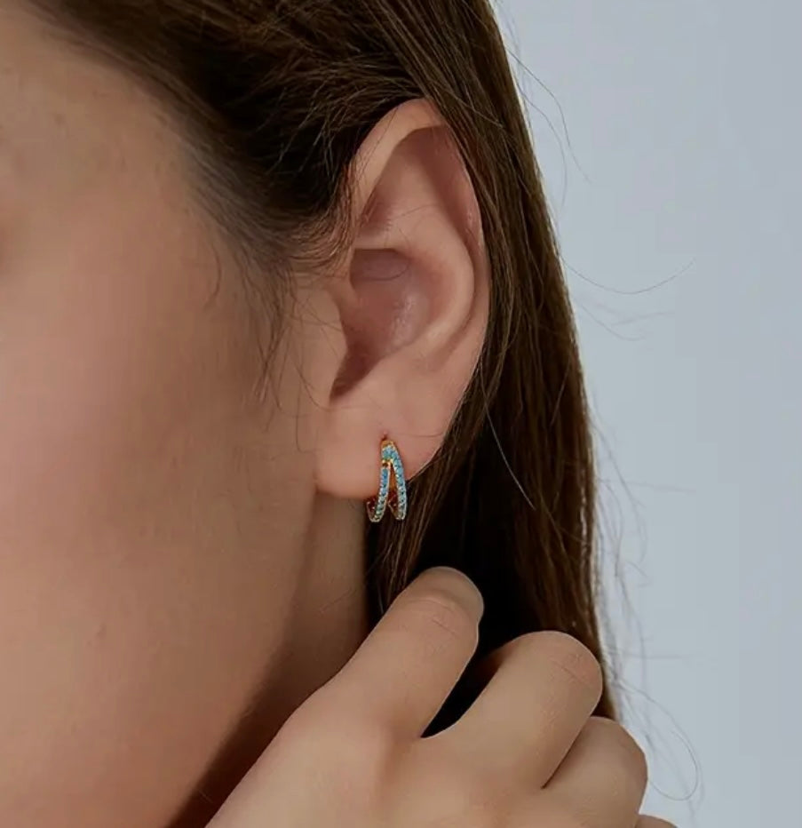 Close-up of an ear wearing a small hoop earring with a blurred background