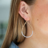 Gold hoop earring with light blue beads worn by a person