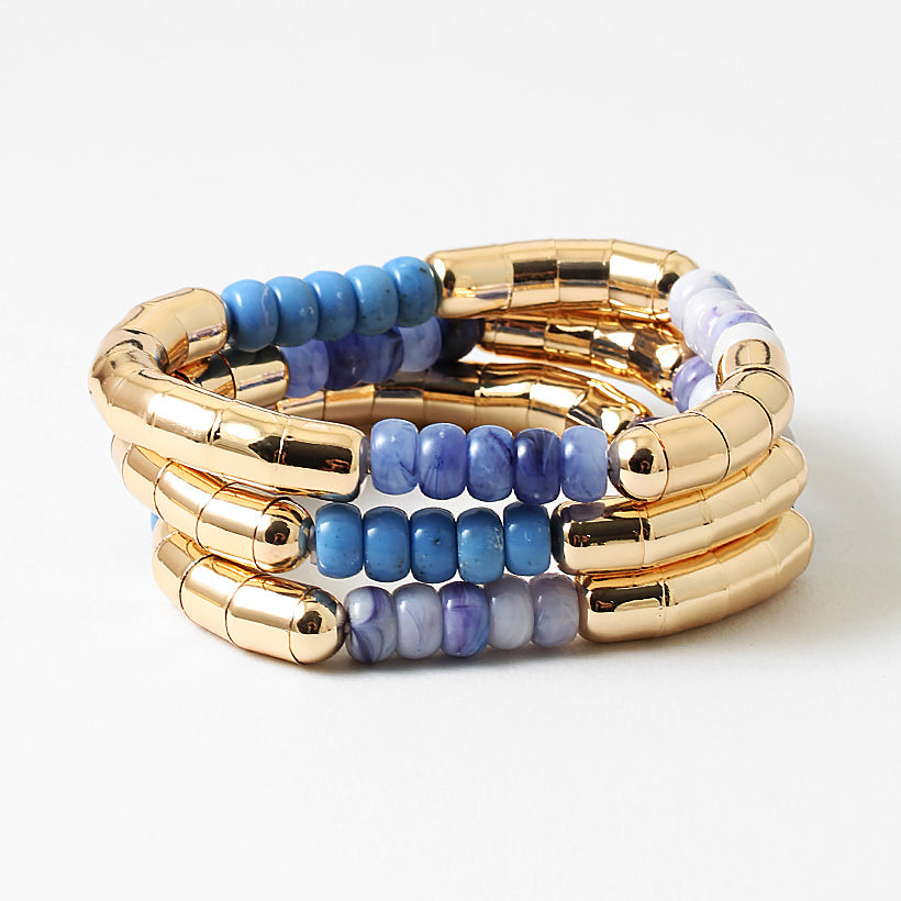 Set of gold and blue beaded bracelets on a white background