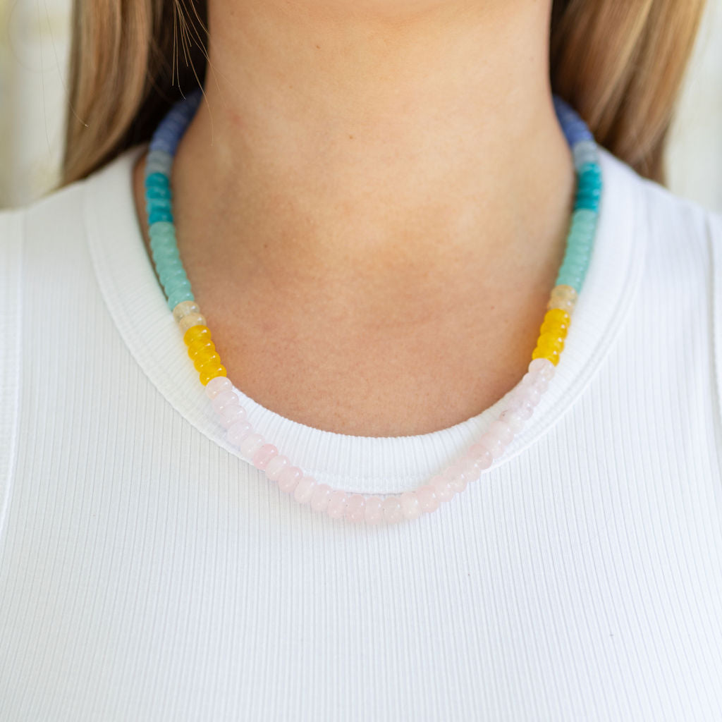 Colorful beaded necklace worn by a person on a white background