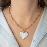 Picture of gold toggle chain with a large white heart pendant bordered by gold.