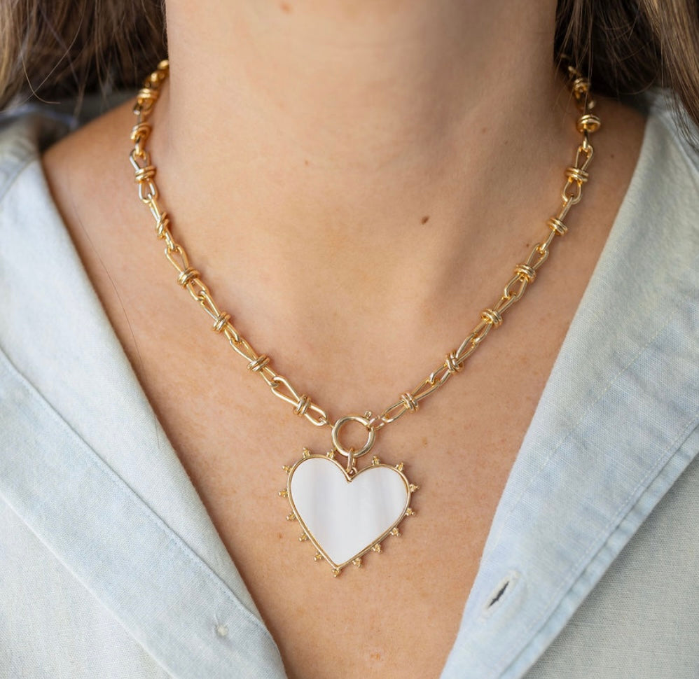 Picture of gold toggle chain with a large white heart pendant bordered by gold.