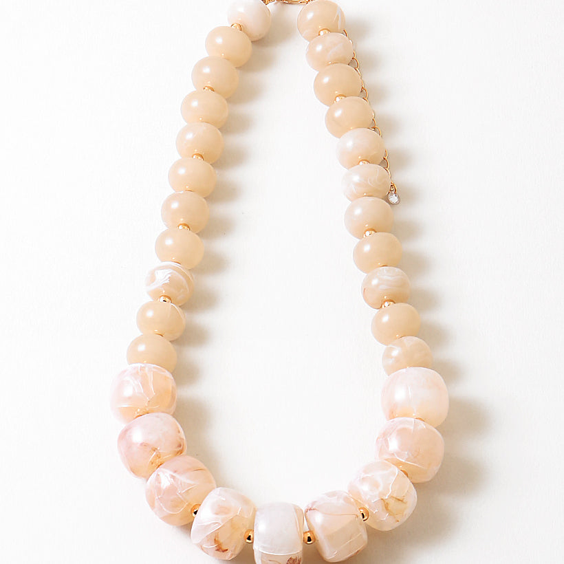 Statement necklace with large pink and white beads on a white background