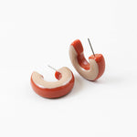 Pair of red and beige hoop earrings on a white background