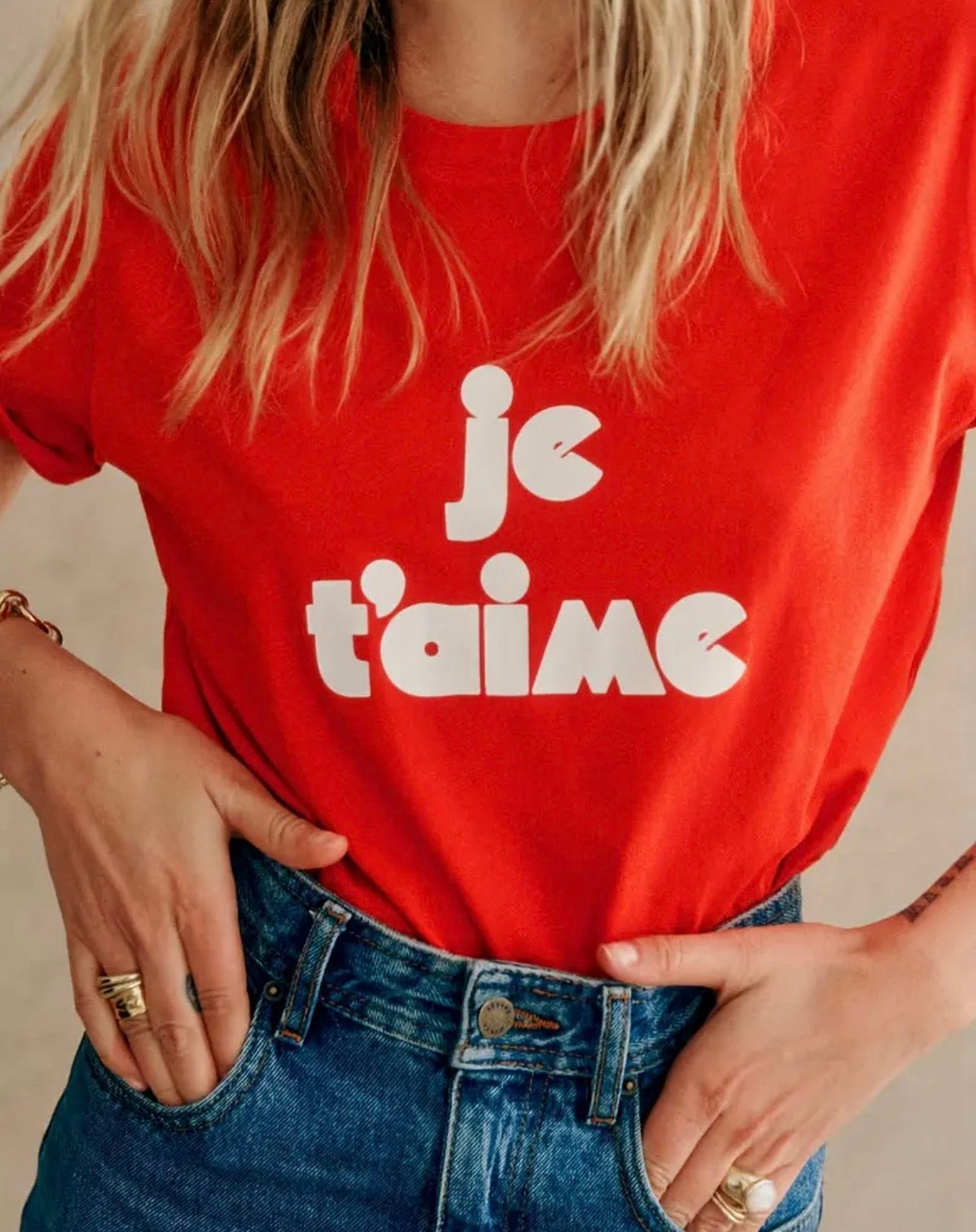 Person wearing a red t-shirt with 'je t'aime' text, standing against a neutral background