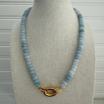 Necklace with blue beads and a gold clasp on a mannequin bust.