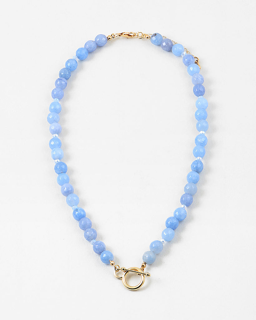 Light blue bead necklace with a large gold toggle clasp at its center.