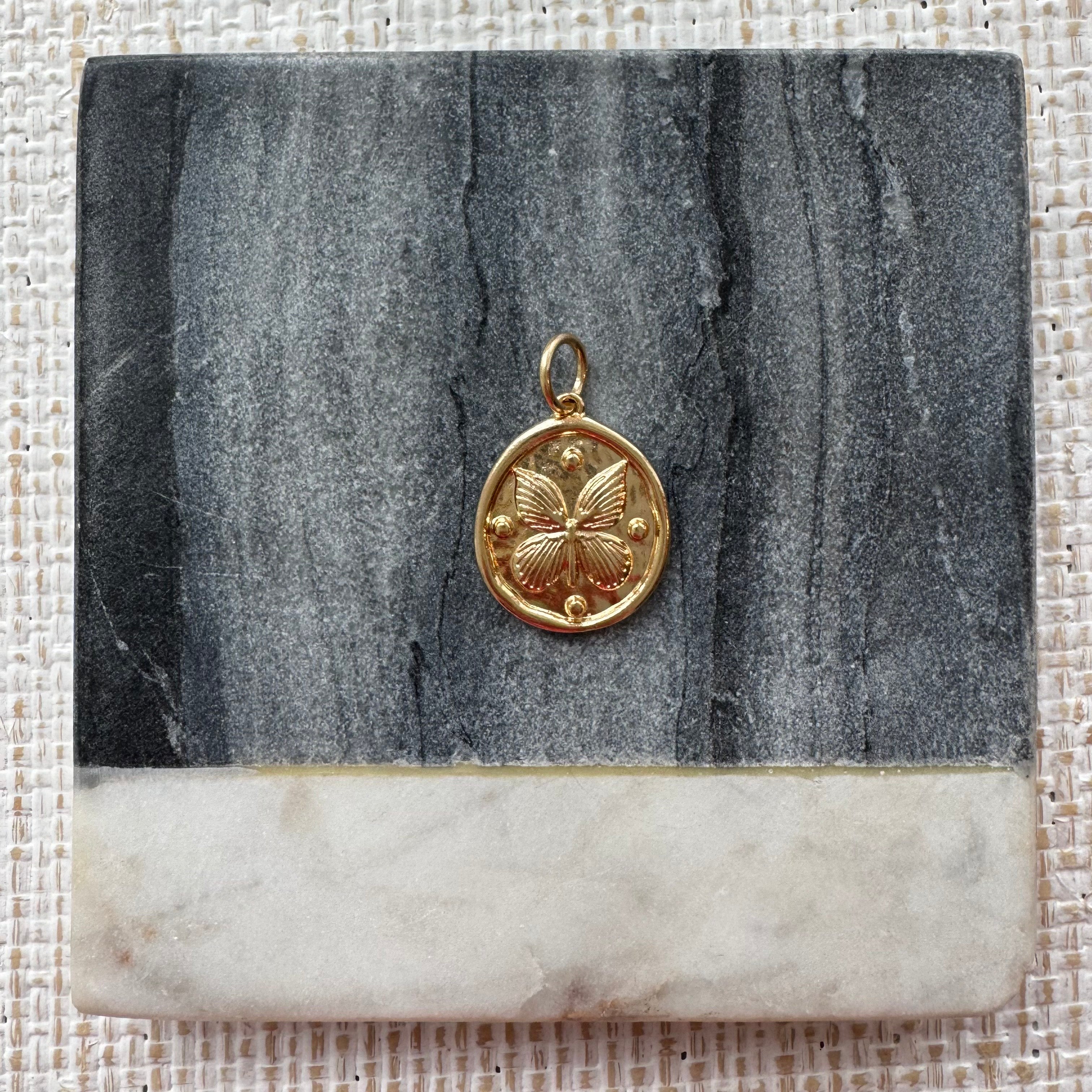 Picture of a gold disc pendant with a butterfly design.