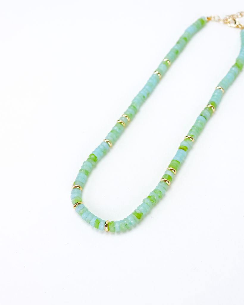 Necklace with light blue and green beads and gold accents on a white background