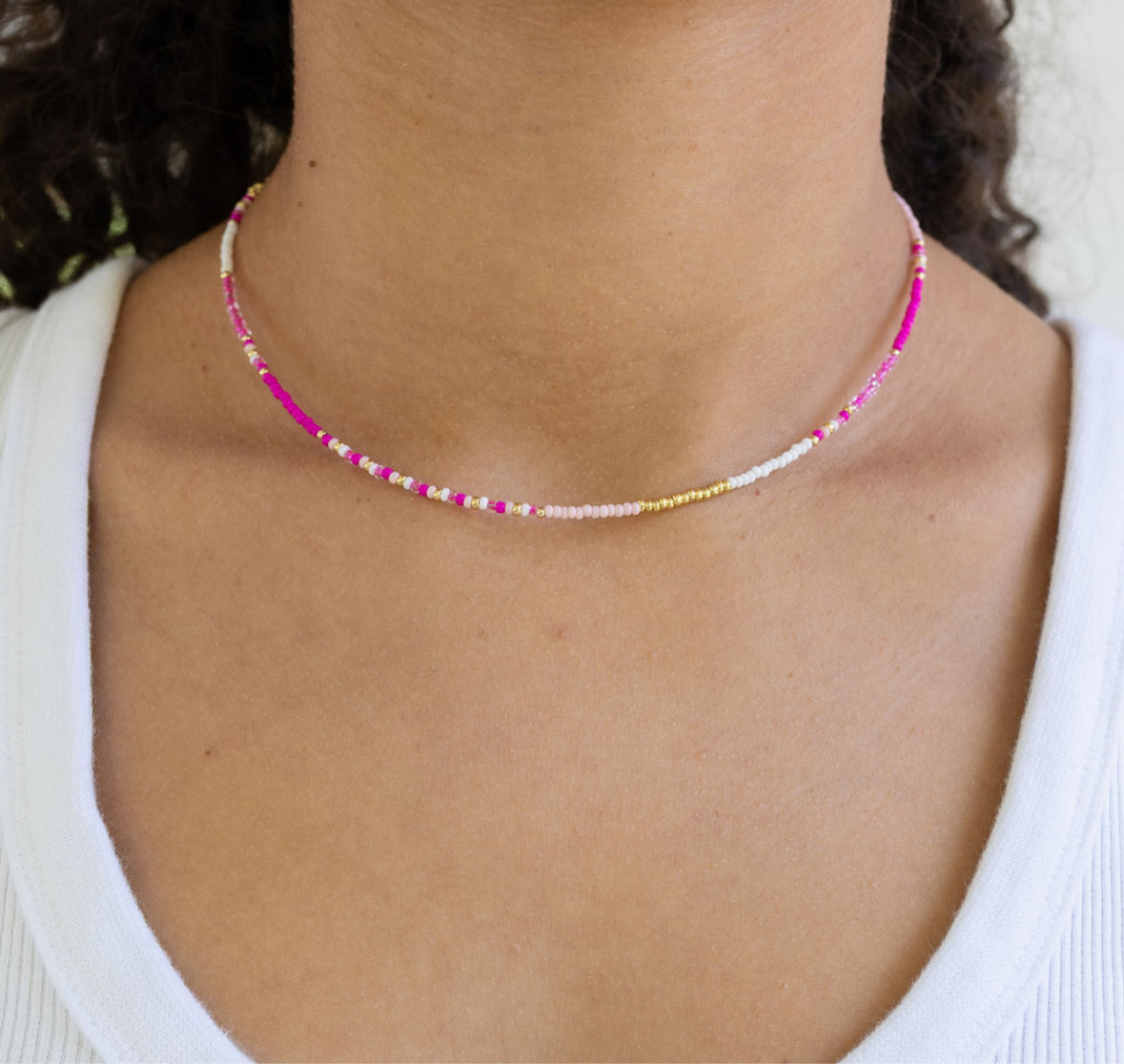 Dainty seed bead necklace made of white and pink beads with gold spacer beads