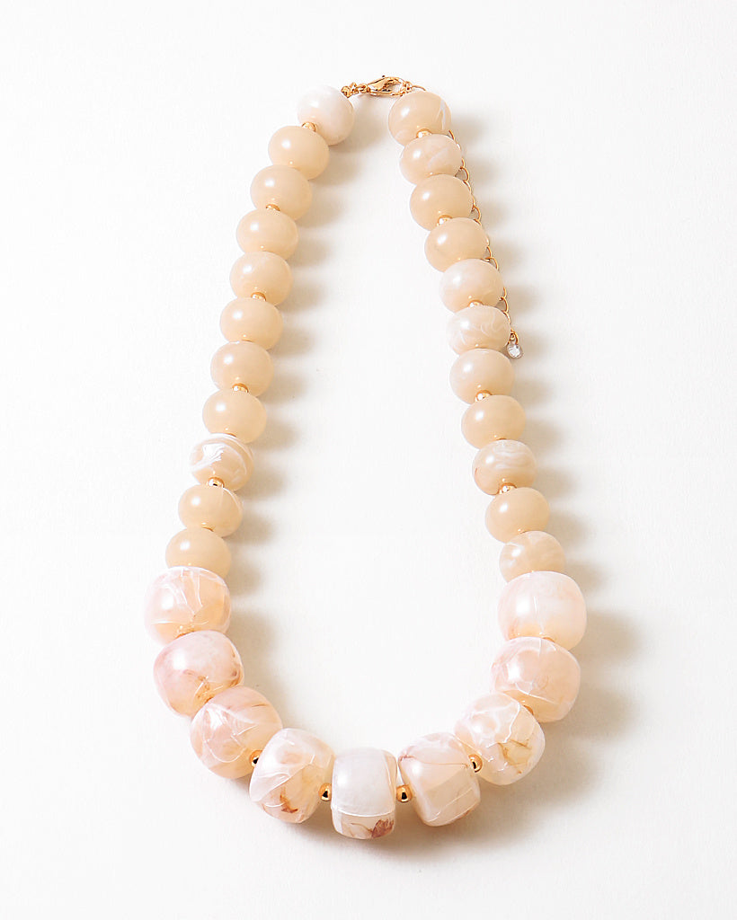 Statement necklace with large pink and white beads on a white background