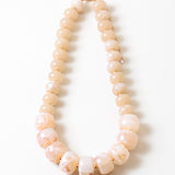 Statement necklace with large pink and white beads on a white background