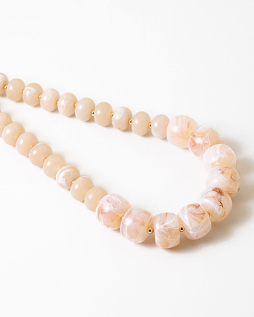 Statement necklace with large pink beads on a white background