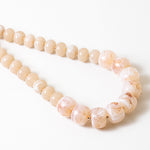 Statement necklace with large pink beads on a white background