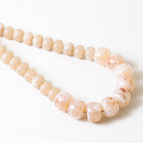 Statement necklace with large pink beads on a white background