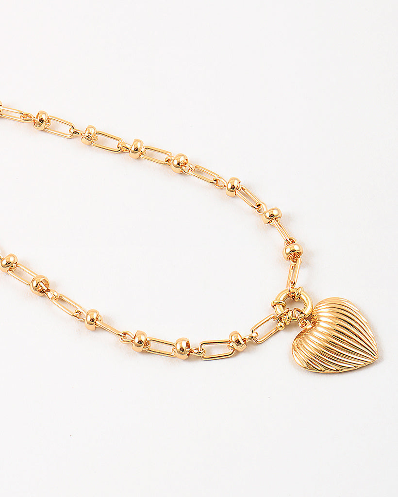 Gold necklace with a heart shaped pendant on a white background