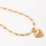 Gold necklace with a heart shaped pendant on a white background