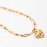 Gold necklace with a heart shaped pendant on a white background