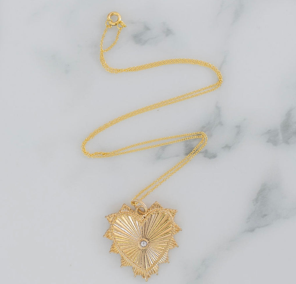Delicate gold chain necklace with a large textured gold heart pendant.
