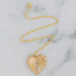 Delicate gold chain necklace with a large textured gold heart pendant.