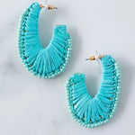 Turquoise beaded and woven hoop earrings on a light gray background