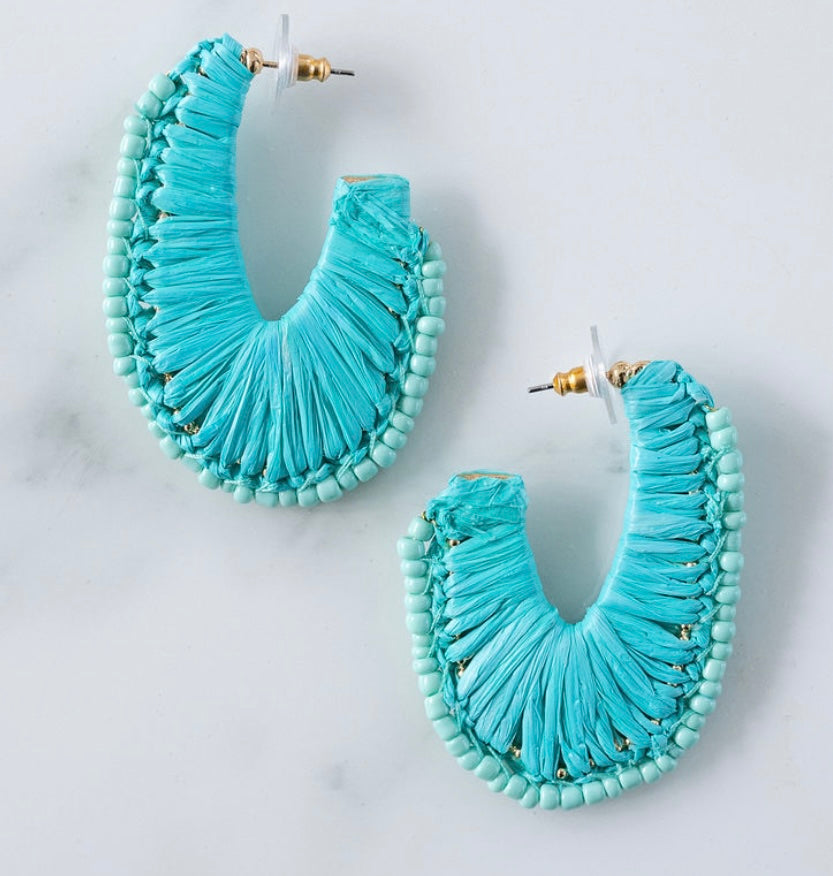 Turquoise beaded and woven hoop earrings on a light gray background