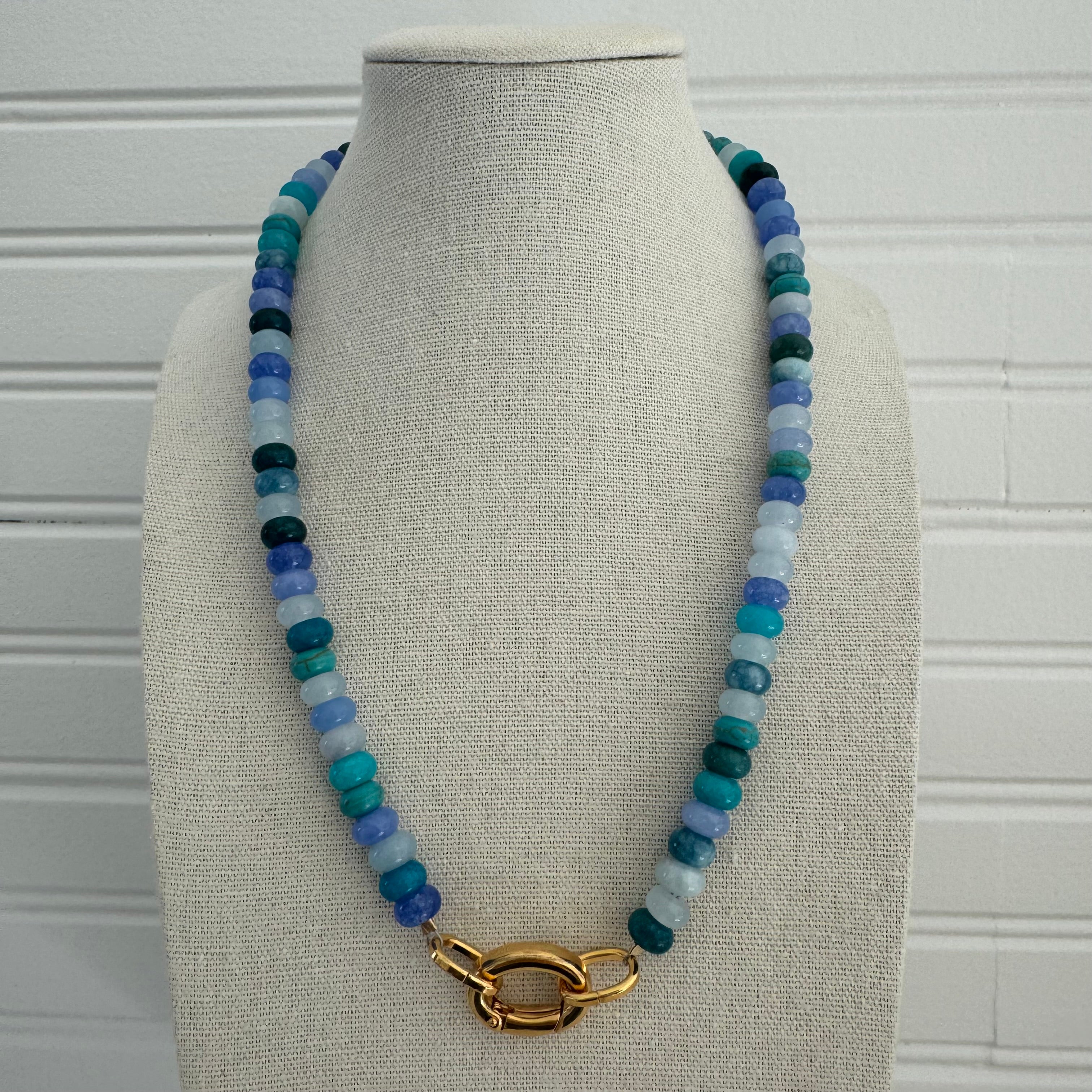 Necklace of shades of dark and light blue beads with a gold clasp.