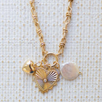 Picture of gold toggle chain with a large gold heart pendant with a diamond in the center, a bubble gold heart and pearl disc charm.