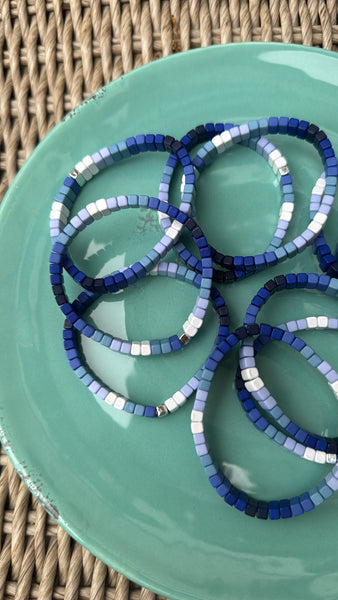 Picture of a green plate holding 8 blue ombre bead bracelets