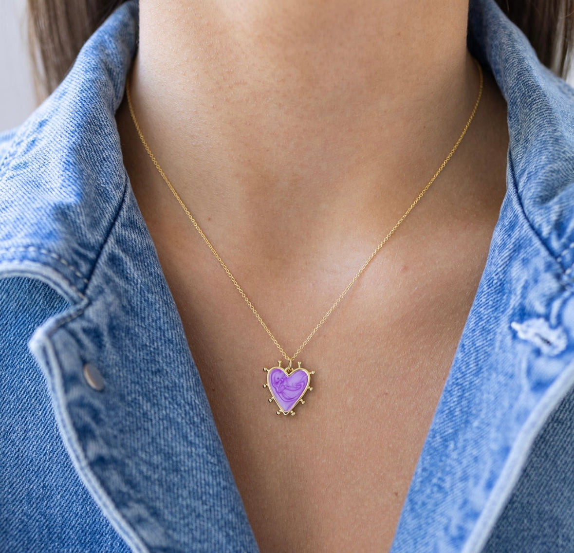Picture of a fine gold chain with a purple heart pendant with gold edging.