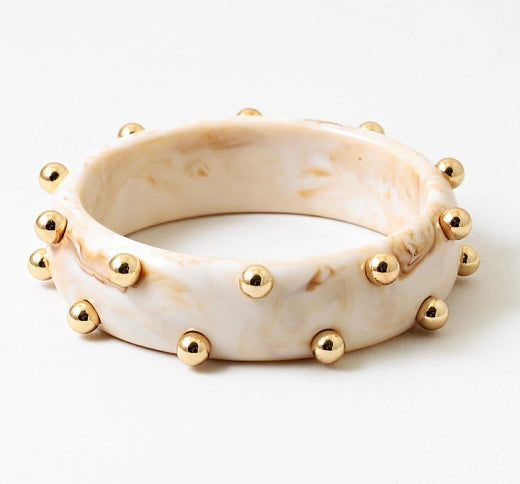 Picture of a marbled ivory colored bangle with inlaid gold beads.