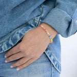 Person wearing a colorful rectangle bead bracelet with a denim jacket