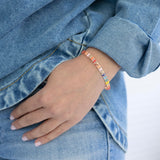 Person wearing a colorful rectangle bead bracelet with a denim jacket