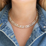 Person wearing a cream chain necklace with a denim jacket