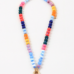 Picture of a bead necklace with a thick gold toggle clasp at its center. Beads are light blue, dark blue, orange, green, orange and yellow.