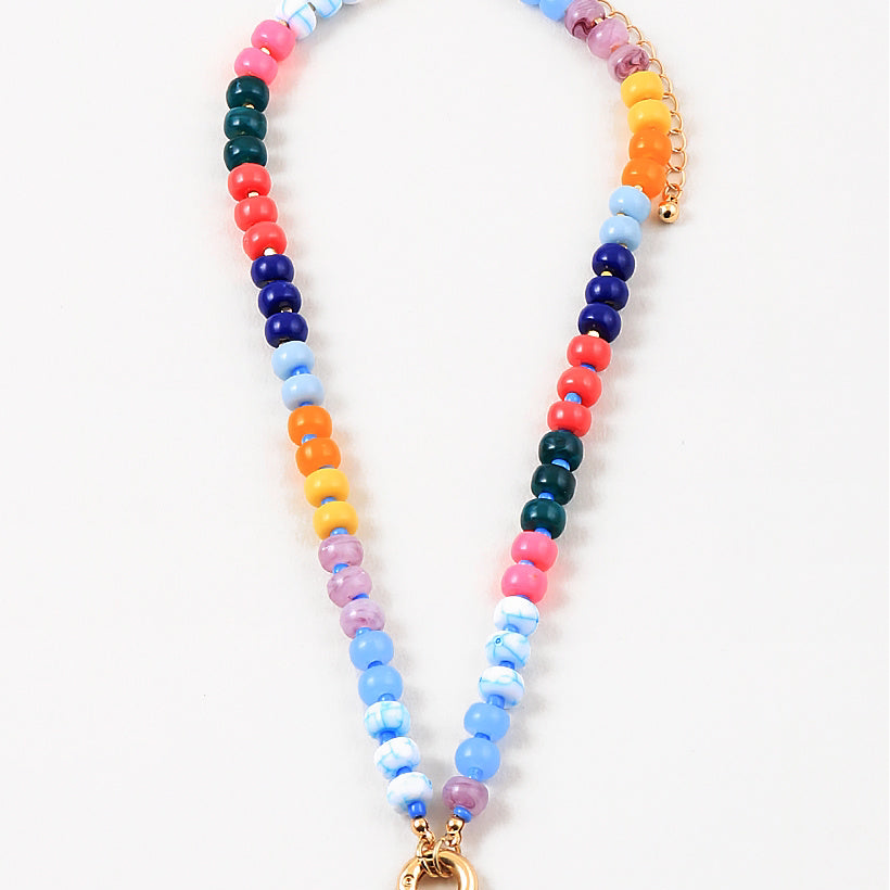Picture of a bead necklace with a thick gold toggle clasp at its center. Beads are light blue, dark blue, orange, green, orange and yellow.