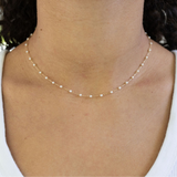 Dainty white pearl necklace on a woman's neck.