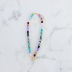 Picture of a multicolored bead necklace in turquoises and purples with a central gold toggle clasp.