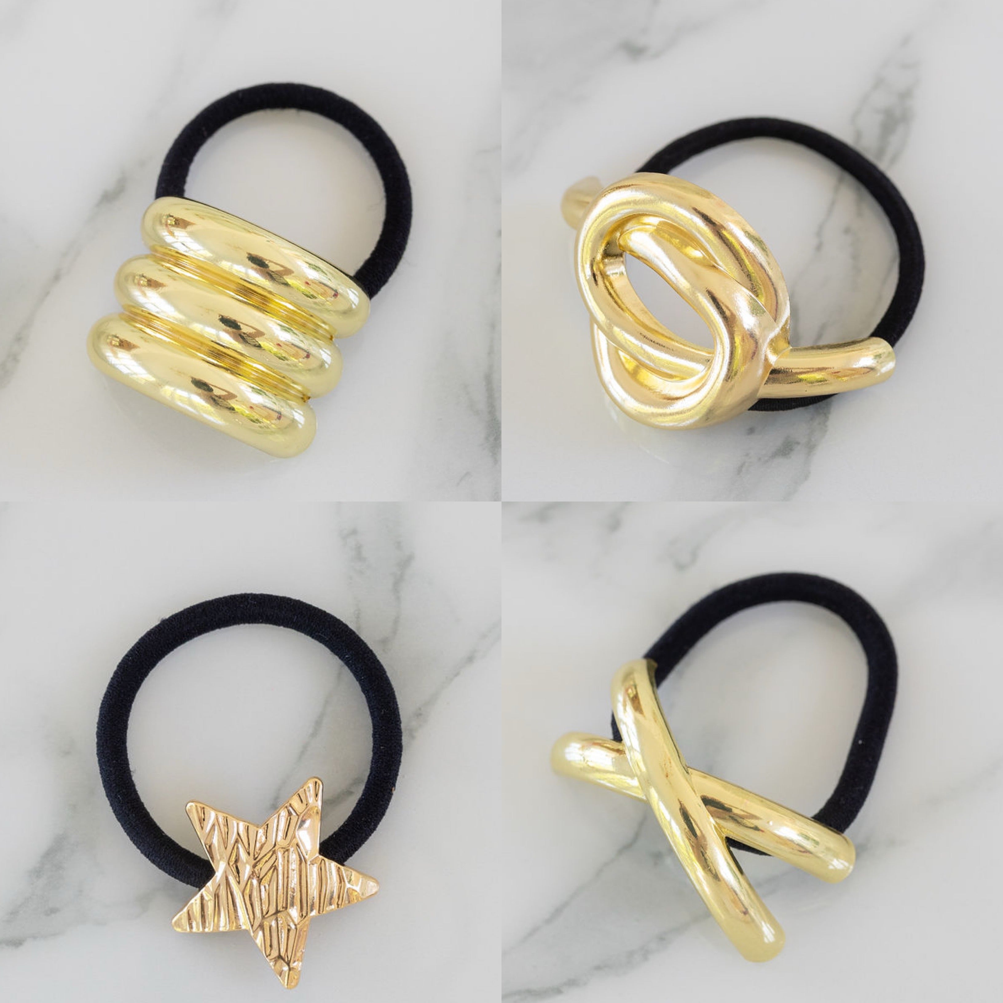 Four gold hair tie holders on black hair ties against a marble background