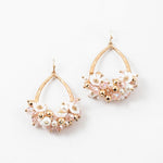Gold and pearl dangle earrings with floral decor on a white background