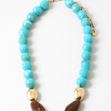 Chunky turquoise beaded necklace with gold and brown bead accents on a white background