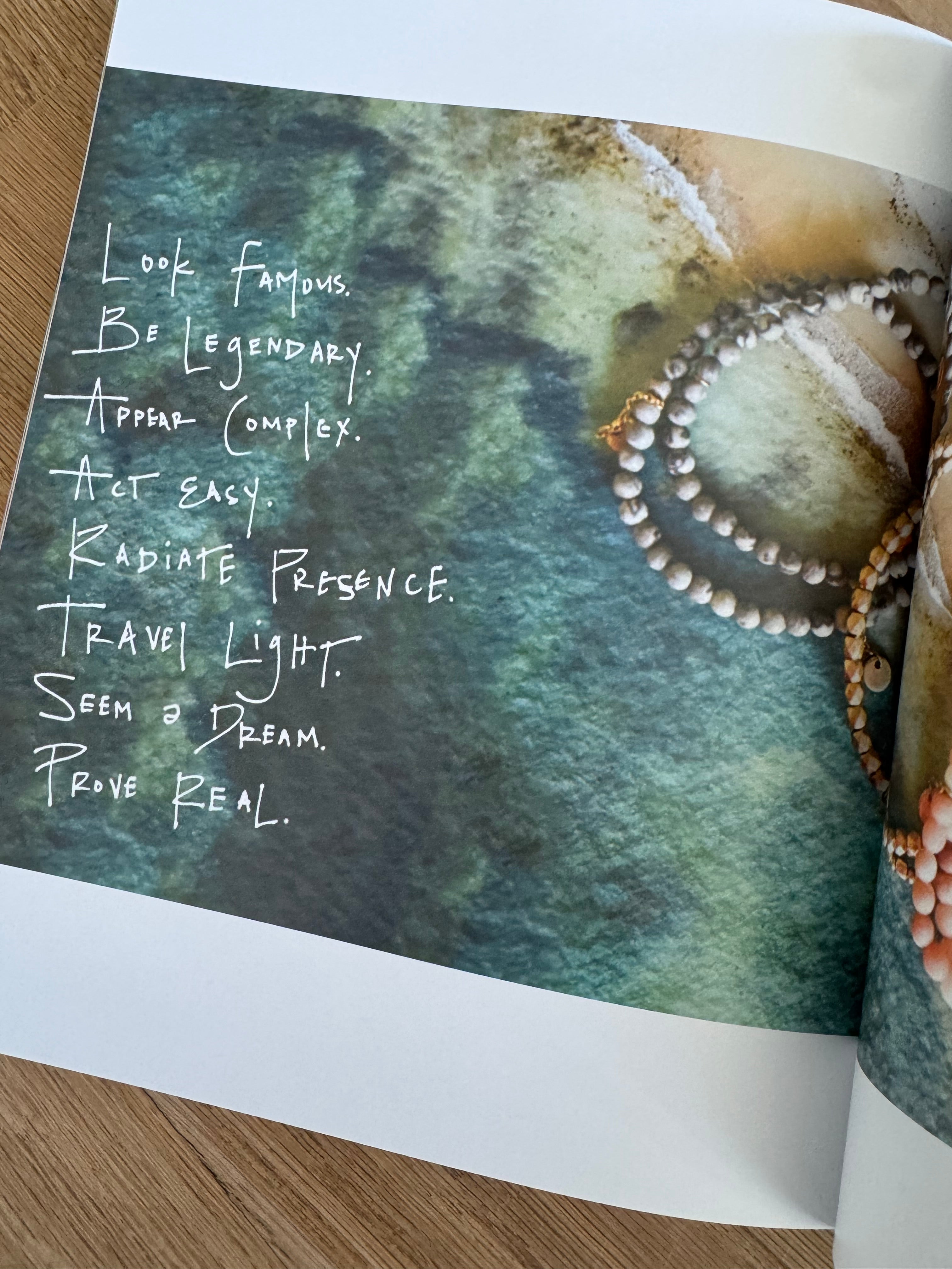 Picture of book page showing aerial beach shot with beaded jewelry overlayed and a poem written.