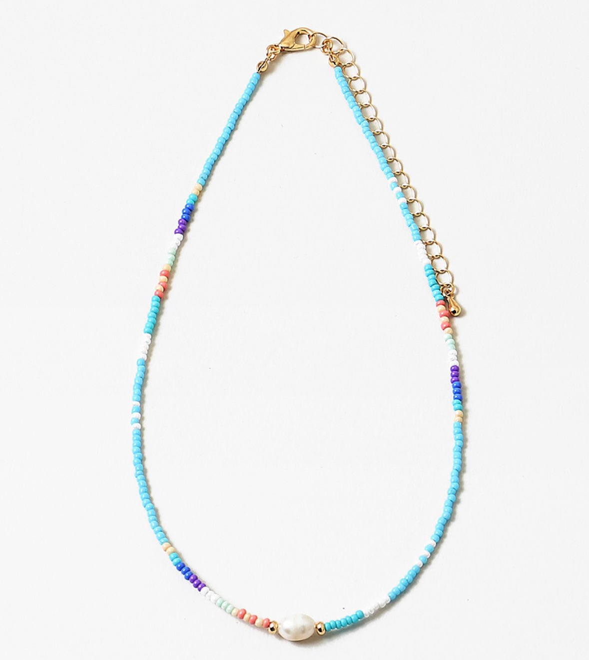 Necklace with different shades of blue beads and gold chain with a fresh water pearl on a white background