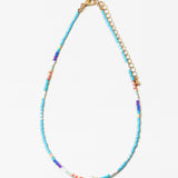 Necklace with different shades of blue beads and gold chain with a fresh water pearl on a white background