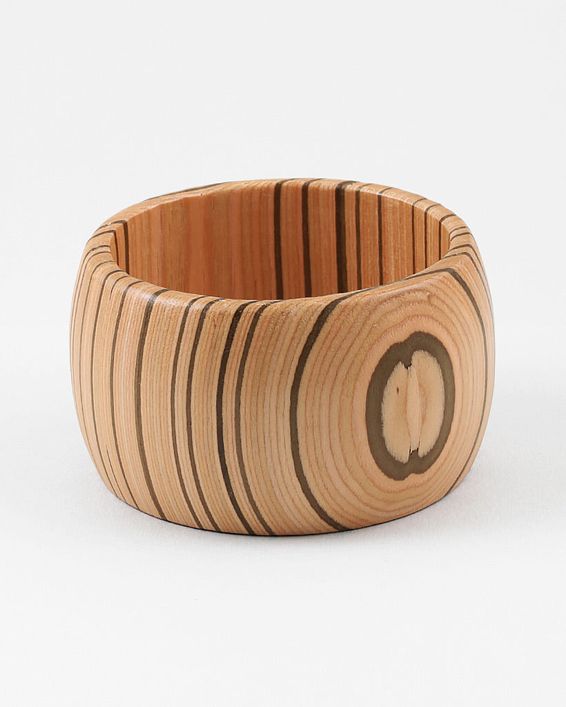 Wooden cuff bracelet with a circular wood grain design on a white background