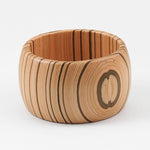 Wooden cuff bracelet with a circular wood grain design on a white background