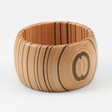 Wooden cuff bracelet with a circular wood grain design on a white background