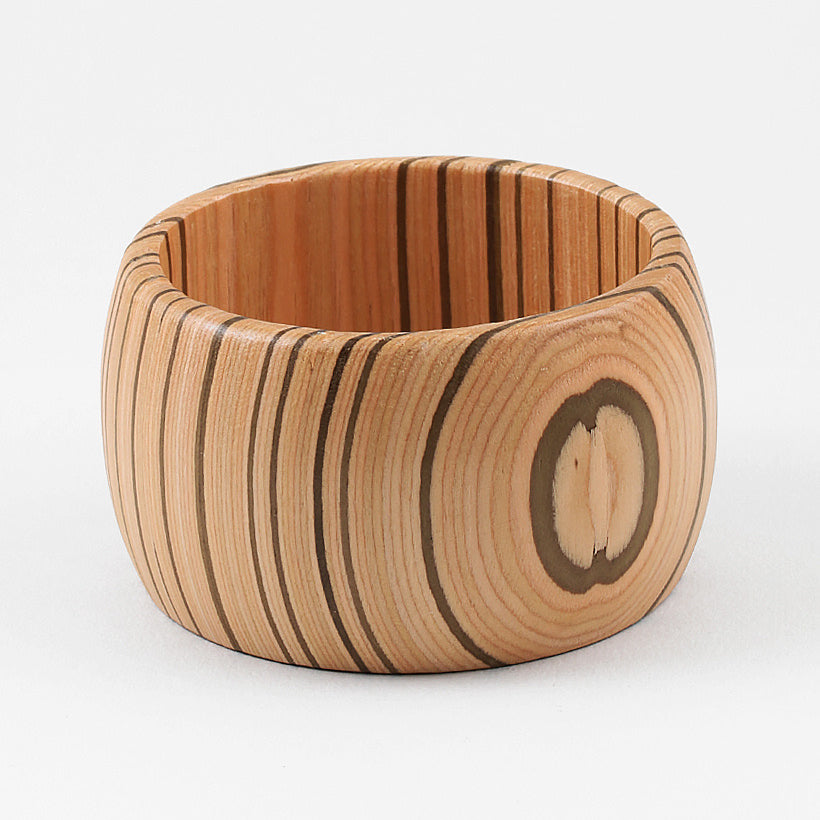 Wooden cuff bracelet with a circular wood grain design on a white background