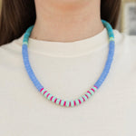 Picture of model wearing a beaded blue, turquoise, pink and light blue necklace.