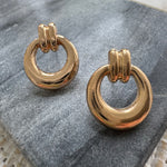 Pair of gold hoop earrings on a gray stone surface